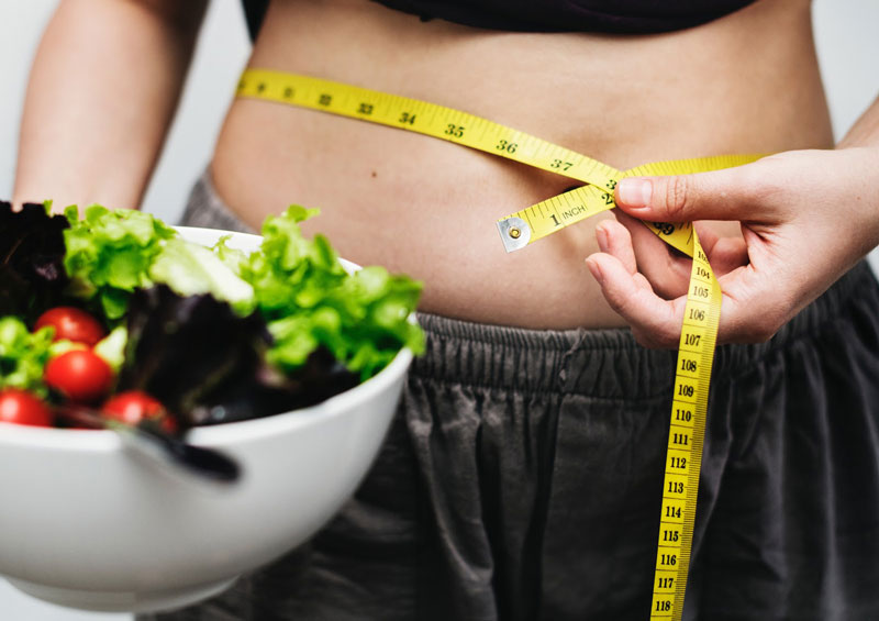 holding salad while measuring stomach