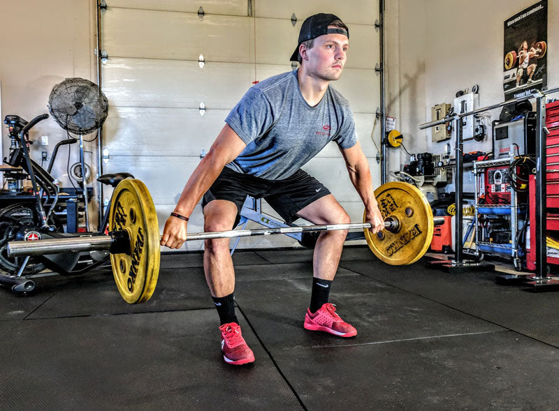 Man Deadlifts Barbell Weights